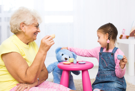 little girl plays with grandmother with her toysの写真素材