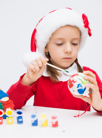 little girl paints New Year ball for Xmas treeの写真素材