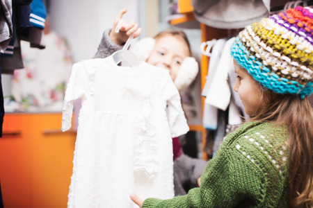 two cute little girls shopping for clothes at a retail storeの写真素材