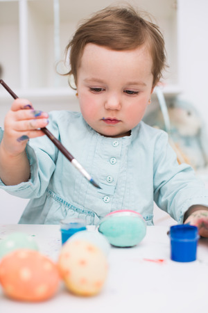 Cute smiling little girl painting colorful easter eggsの写真素材