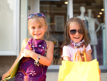 two cute little girls with shopping bags in cityの写真素材