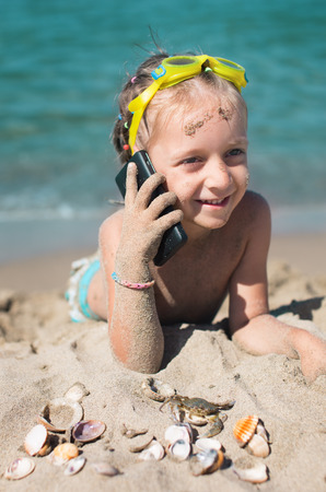 summer portrait of a cute little girl child  speaks on the phoneの写真素材