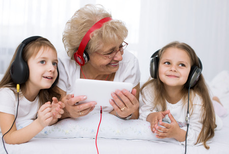 grandmother with granddaughters  listening for the music using headphonesの写真素材
