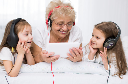 grandmother with granddaughters  listening for the music using headphonesの写真素材