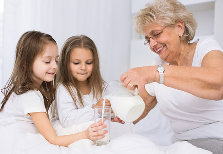 Beautiful grandmother with granddaughter drinking milk, healthcare concept.の写真素材