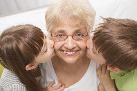 portrait of a cute grandchildren kissing grandmotherの写真素材
