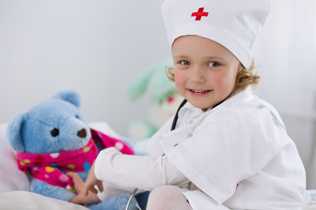 cute little girl dressed as doctor playing with toyの写真素材