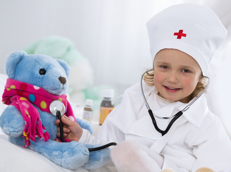 cute little girl dressed as doctor playing with toyの写真素材