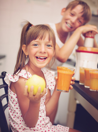 cute kids making carrot and apple juice with a juice extractorの写真素材