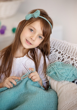 Closeup ofcute little girl0knitting with knitting-needle at homeの写真素材