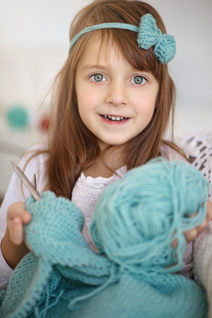 Closeup of cute little girl knitting with knitting-needle at homeの写真素材