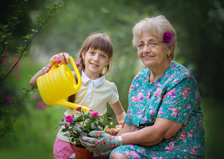 Happy Grandmother with her granddaughter working in the gardenの写真素材