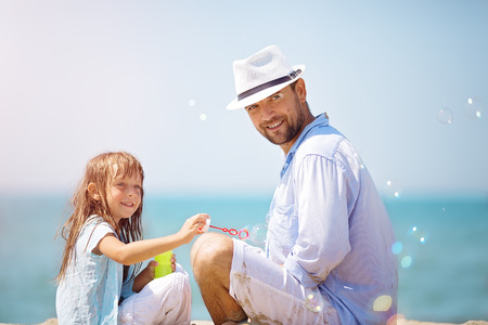 Happy father with his daughter making soap bubbles during summer vacationの写真素材
