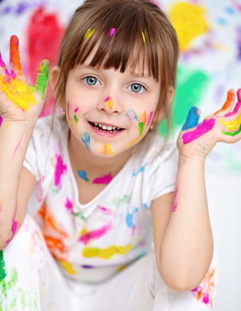 little girl showing her hands painted in bright colorsの写真素材