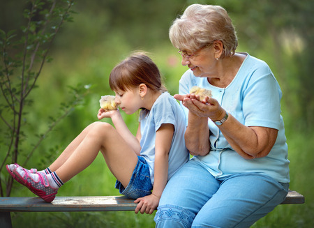 Grandmother with grandaughter are playing with chickens outdoorsの写真素材