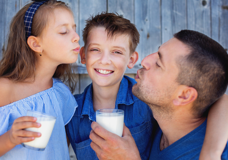 Father with children are drinking milk and having funの写真素材