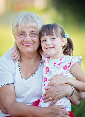 Closeup summer portrait of happy grandmother with granddaughter outdoorsの写真素材