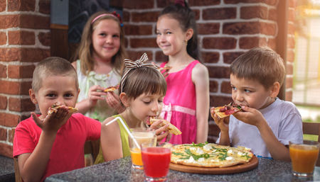 Happy children eating pizza and having fun togetherの写真素材
