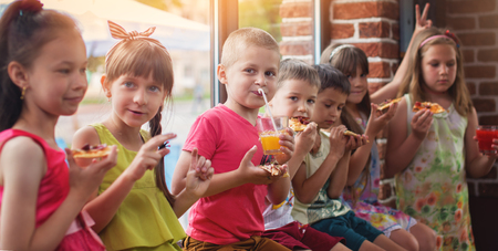 Happy children eating pizza and having fun togetherの写真素材