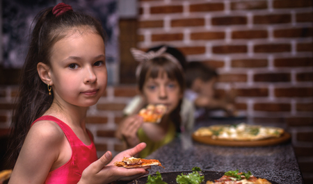 Happy children eating pizza and having fun togetherの写真素材