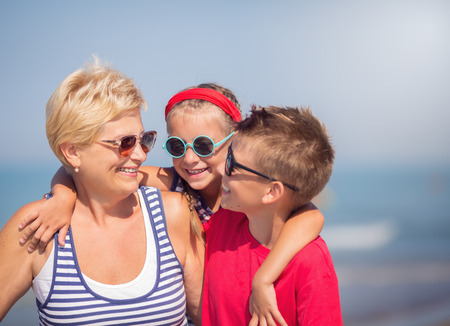 Summer holiday. Grandmother with grandchildren are walking on the sea beach