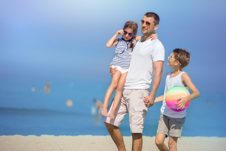 Father with children playing football on the beach at the day time. の写真素材