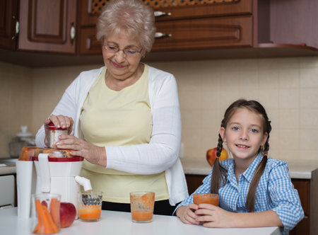 Grandmother with grandchildren are making fresh apple and carrot juiceの写真素材