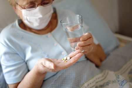 Medicine and healthcare concept. Senior woman with pills and glass of water at homeの写真素材