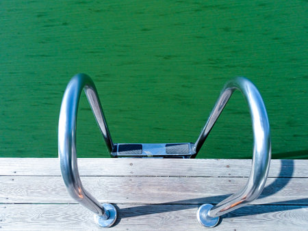Blooming green water in the lake. Handrails for launching into the waterの写真素材