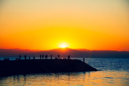 Silhouettes of people against the background of sunsetの写真素材