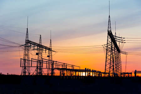 High voltage electric poles and transmission lines. Electricity poles at sunset. High voltage grid towers with wire cable at distribution station.の写真素材