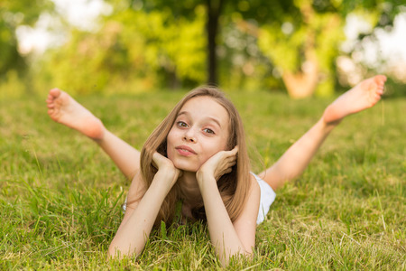 Portrait of a beautiful young girl lying on the grass outdoors in summerの写真素材