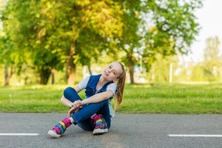portrait of a beautiful smiling girl sitting on the asphaltの写真素材