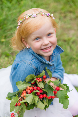 Portrait of a cute little pin-up girl on the nature. Portrait of a beautiful redhead child with a sweet smile. The charming redhead kidの写真素材
