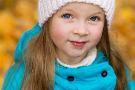 Portrait of a beautiful girl in a blue coat outdoors in autumn. Child in autumn parkの写真素材