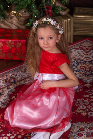 Little beautiful girl in red dress at the Christmas tree. Portrait of cute baby in the New Year decorationsの写真素材