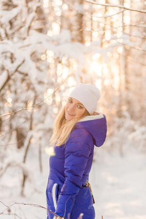 The girl have a rest in the winter woods.  Young woman walking through the snow in winter parkの写真素材