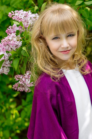Young woman with flowers in green park. Portrait of cute young blonde girl looking at youの写真素材
