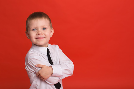 Little boy posing in the studio on a red background.の写真素材