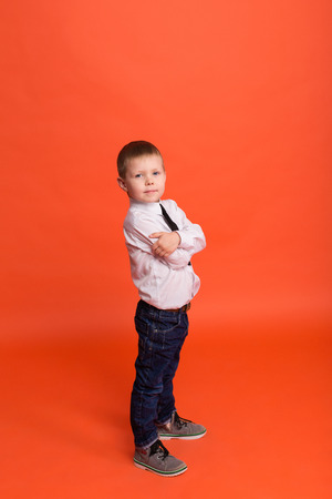 Little boy posing in the studio on a red background.の写真素材