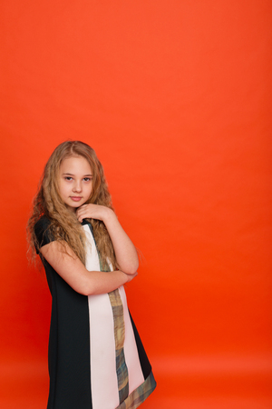 Girl in beautiful stylized dress on a red background in the studio. Blonde girl posing in studioの写真素材