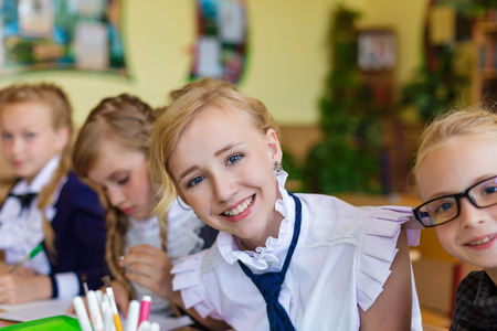 Girls at school desks. Girlfriends are sitting at school with books, notebooks and telephones....