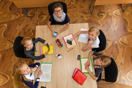 Girls at school desks. Girlfriends are sitting at school with books, notebooks and telephones....