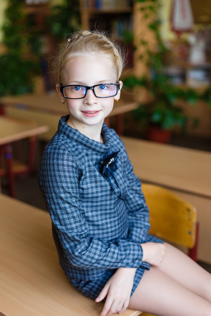 Girl at school desk. Child is sitting at school with books, notebooks and telephones. Child study in the school room. Selfieの写真素材