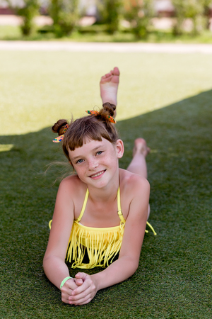 Beautiful girl in a swimsuit on the grass by the pool in summerの写真素材