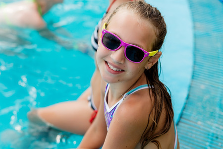 Beautiful girl in a swimsuit swims in the pool by the summerの写真素材