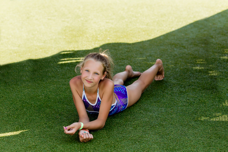 Beautiful girl in a swimsuit on the grass by the pool in summerの写真素材