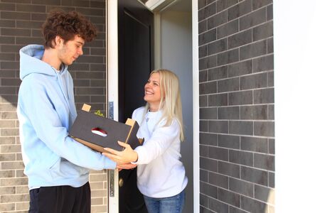 Young guy delivers groceries to a woman in a boxの写真素材