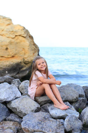A child on the stones near the sea in summer.の写真素材