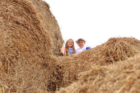 Two children are high under the sky on a haystack in the hay season.の写真素材